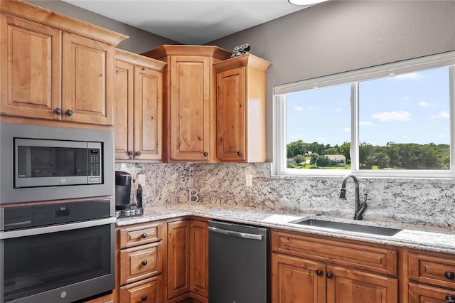 kitchen featuring sink, backsplash, stainless steel appliances, and light stone countertops