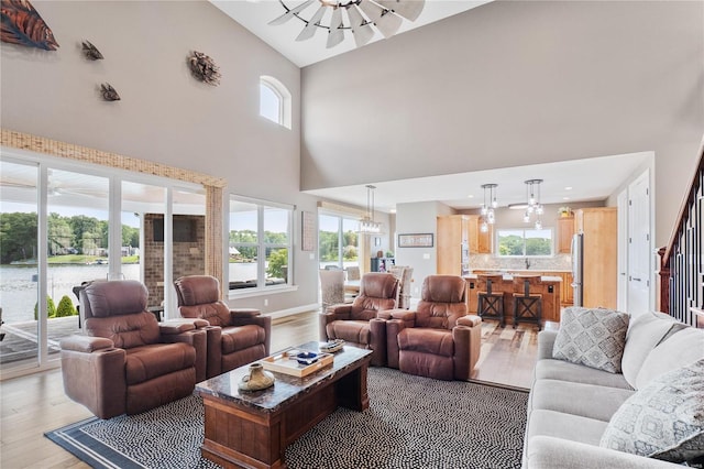 living room featuring light hardwood / wood-style floors, ceiling fan, and a high ceiling