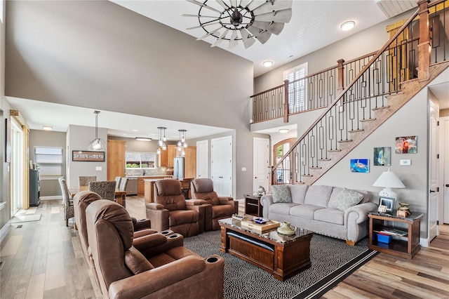 living room featuring a towering ceiling, a wealth of natural light, and light wood-type flooring