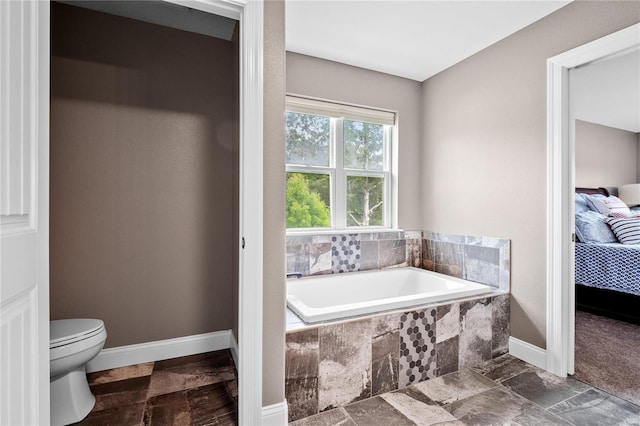 bathroom featuring tiled bath and toilet