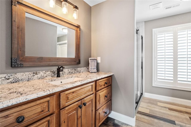 bathroom with a shower with door, vanity, and hardwood / wood-style floors