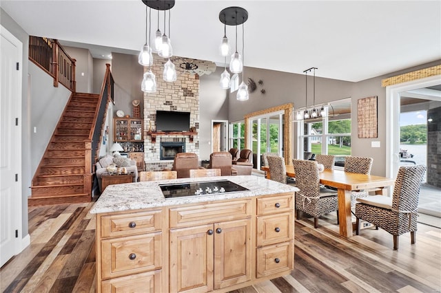 kitchen featuring dark hardwood / wood-style floors, decorative light fixtures, a center island, a brick fireplace, and black electric cooktop