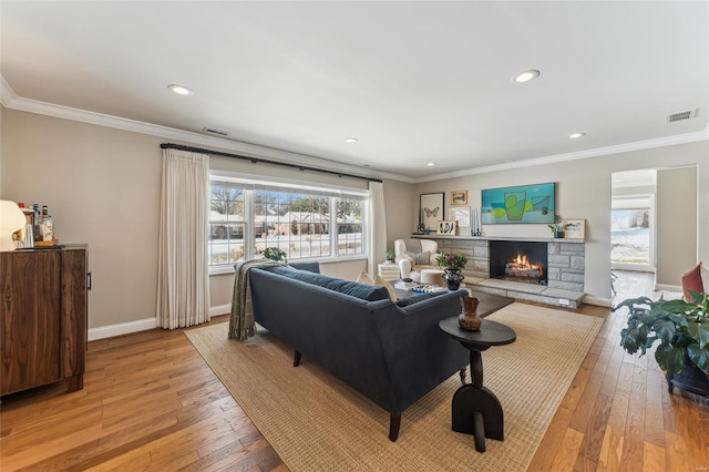 living area with baseboards, light wood-style floors, visible vents, and crown molding