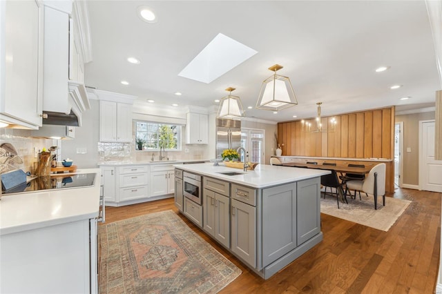 kitchen with gray cabinetry, light countertops, a center island with sink, and white cabinetry