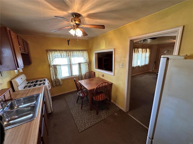 kitchen with sink, fridge, white gas range oven, ceiling fan, and dark carpet