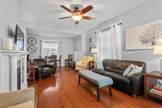 living room with a high end fireplace, hardwood / wood-style floors, and ceiling fan