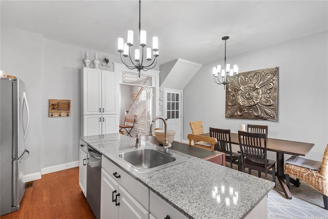 kitchen with white cabinetry, stainless steel appliances, sink, and an island with sink