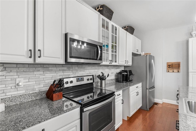 kitchen featuring decorative backsplash, dark wood-type flooring, stainless steel appliances, and white cabinets