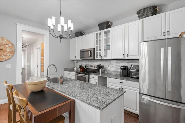 kitchen featuring sink, light stone counters, a notable chandelier, stainless steel appliances, and white cabinets