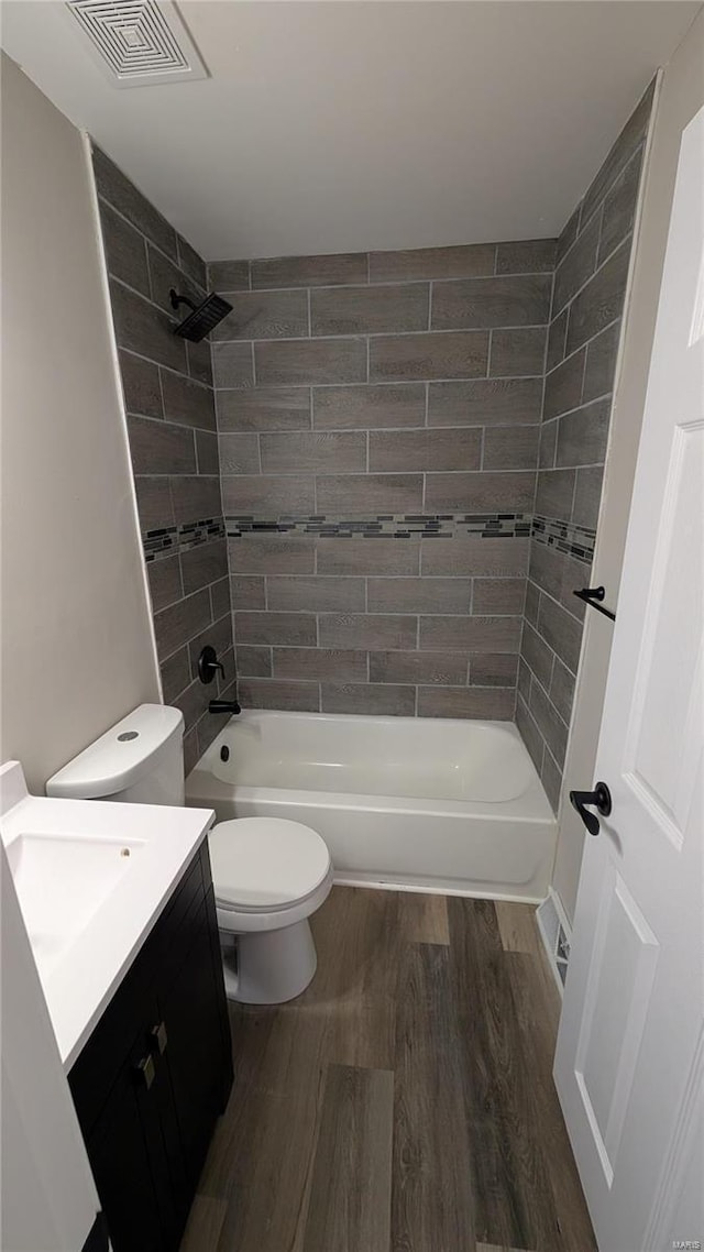 full bathroom with hardwood / wood-style flooring, vanity, toilet, and tiled shower / bath combo