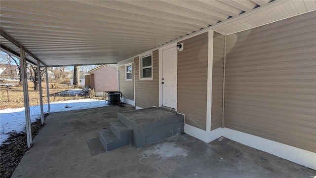 snow covered patio with cooling unit and a carport