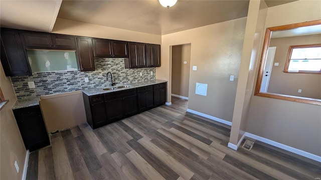 kitchen featuring dark hardwood / wood-style floors, sink, backsplash, light stone counters, and dark brown cabinets