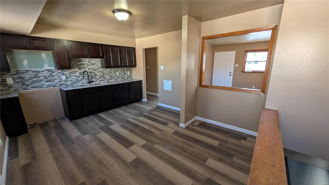 kitchen featuring dark brown cabinetry, backsplash, dark hardwood / wood-style flooring, and sink