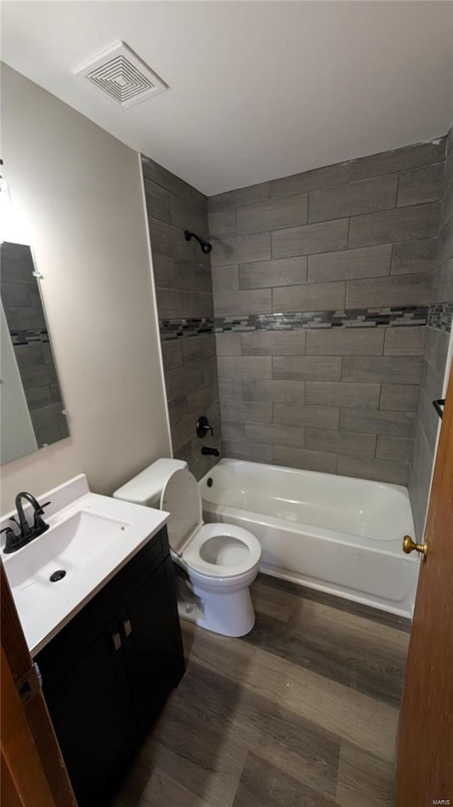 full bathroom featuring tiled shower / bath combo, wood-type flooring, vanity, and toilet