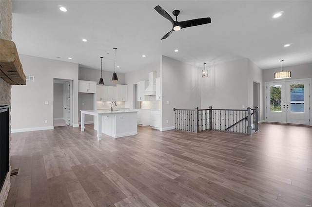 unfurnished living room featuring sink, light hardwood / wood-style flooring, ceiling fan, and french doors