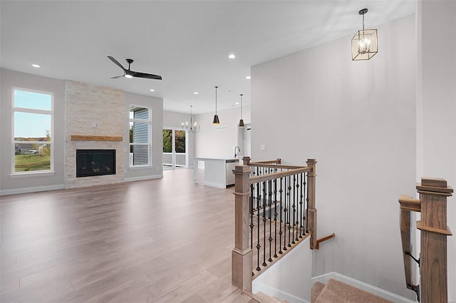 interior space featuring hardwood / wood-style flooring, a fireplace, and ceiling fan with notable chandelier