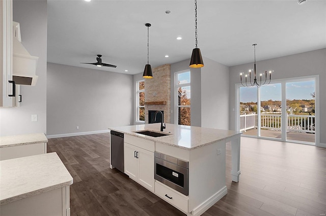 kitchen with sink, white cabinetry, hanging light fixtures, stainless steel appliances, and a kitchen island with sink