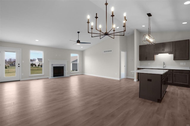 kitchen featuring dark brown cabinetry, decorative light fixtures, a center island, a high end fireplace, and hardwood / wood-style floors