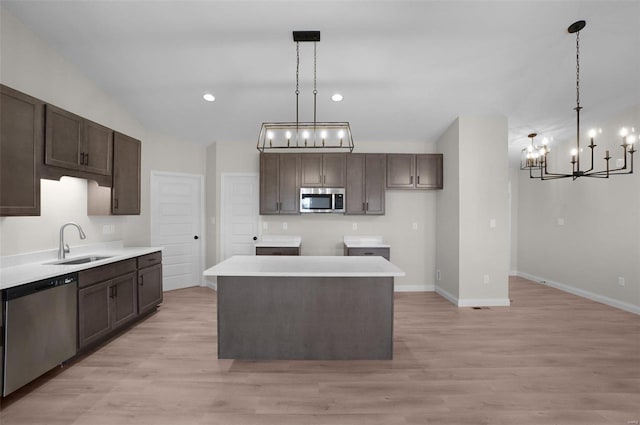 kitchen with pendant lighting, appliances with stainless steel finishes, sink, and a kitchen island