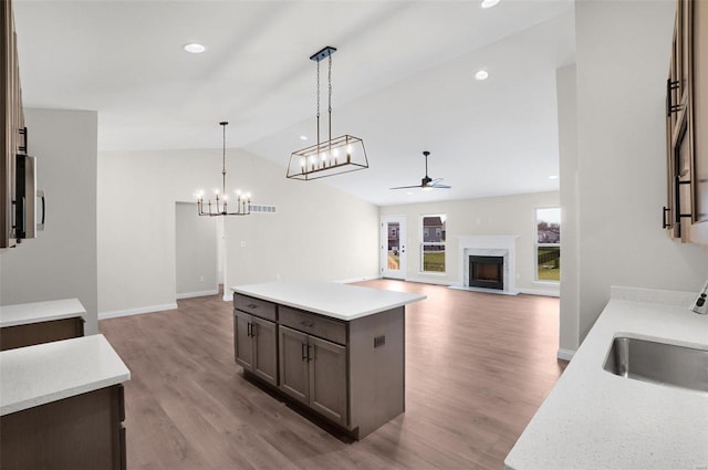 kitchen featuring sink, a kitchen island, pendant lighting, a premium fireplace, and light hardwood / wood-style floors