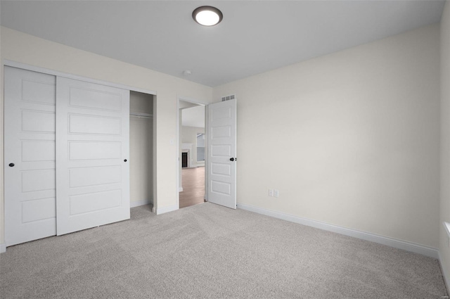 unfurnished bedroom featuring a closet and light carpet