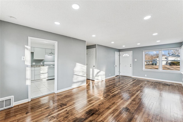 unfurnished living room with light hardwood / wood-style floors and a textured ceiling