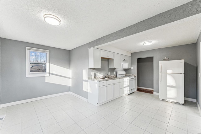 kitchen with sink, white cabinets, light tile patterned floors, light stone countertops, and white appliances