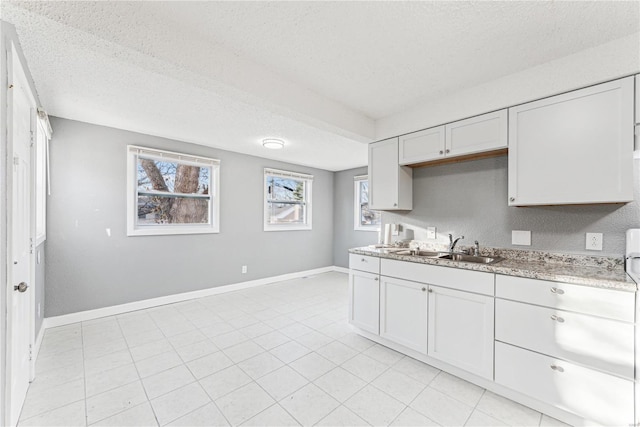 kitchen featuring white cabinetry, light stone countertops, sink, and a textured ceiling