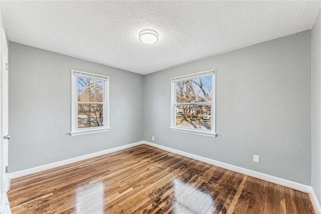 empty room with hardwood / wood-style flooring, plenty of natural light, and a textured ceiling