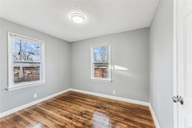 empty room featuring a textured ceiling and dark hardwood / wood-style flooring