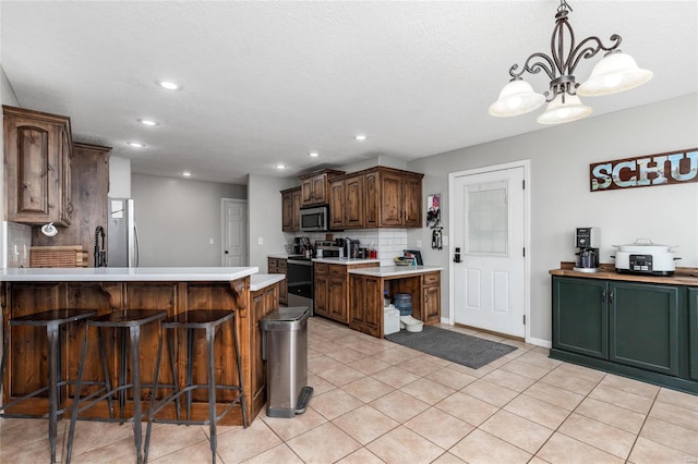 kitchen featuring light tile patterned flooring, a kitchen island, pendant lighting, stainless steel appliances, and decorative backsplash