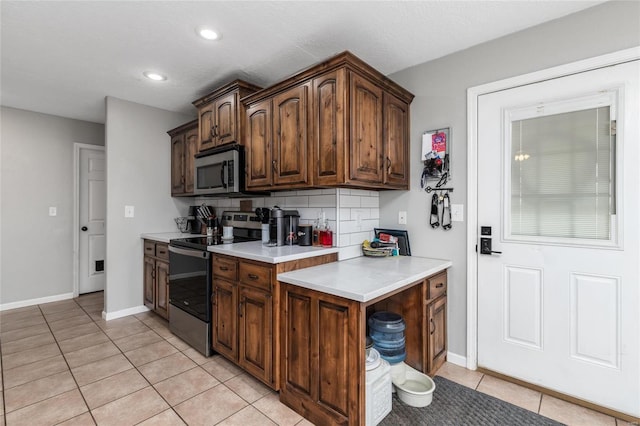 kitchen featuring stainless steel appliances, tasteful backsplash, dark brown cabinets, and light tile patterned floors