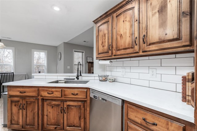 kitchen with sink, decorative backsplash, stainless steel dishwasher, and kitchen peninsula