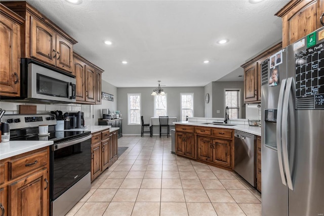 kitchen with sink, an inviting chandelier, light tile patterned floors, pendant lighting, and stainless steel appliances