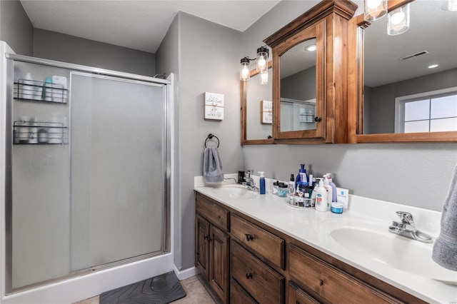 bathroom featuring a shower with door and vanity