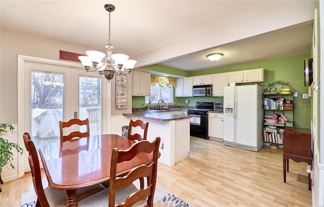 kitchen with white refrigerator with ice dispenser, gas stove, white cabinets, decorative light fixtures, and kitchen peninsula