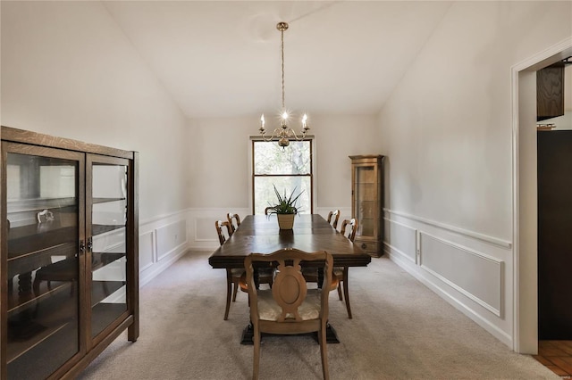 dining room featuring lofted ceiling, light colored carpet, and a chandelier