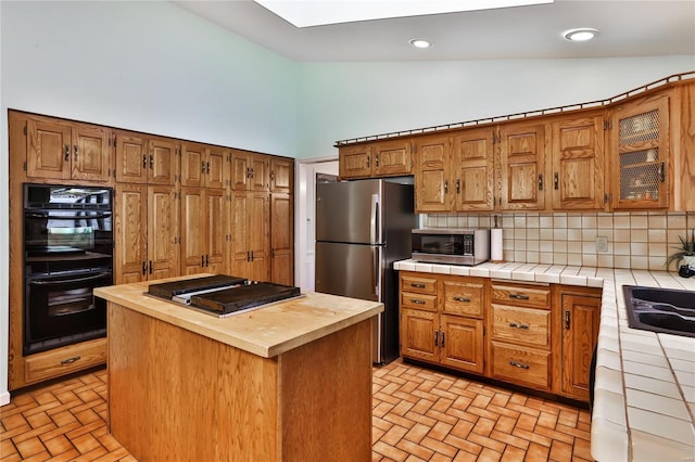 kitchen featuring stainless steel appliances, a center island, tile counters, and backsplash