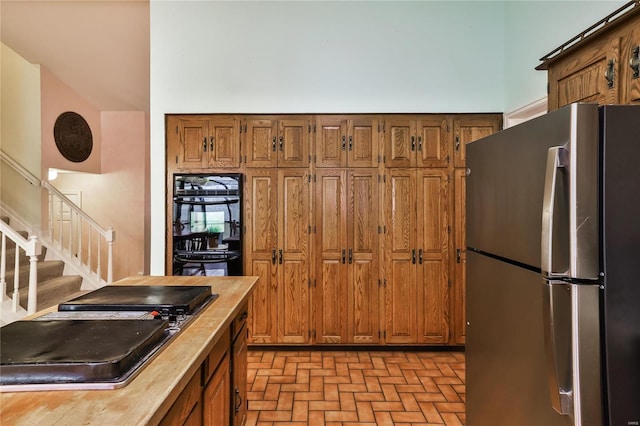 kitchen with sink, black double oven, and stainless steel refrigerator