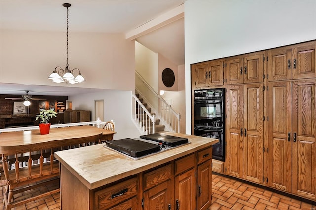 kitchen with high vaulted ceiling, double oven, beamed ceiling, decorative light fixtures, and a center island