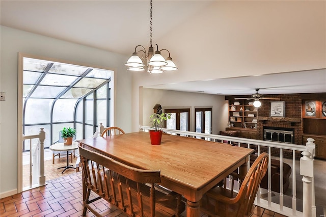 dining room featuring a fireplace, ceiling fan with notable chandelier, and plenty of natural light