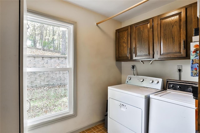 clothes washing area featuring washer and dryer, cabinets, and a healthy amount of sunlight