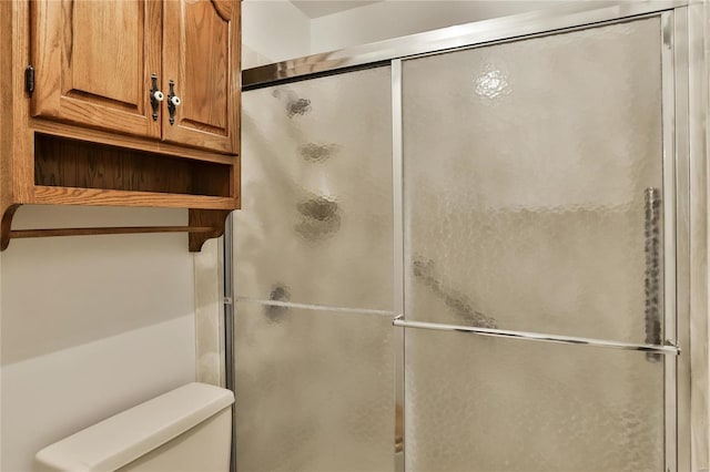 bathroom featuring toilet and a shower with shower door