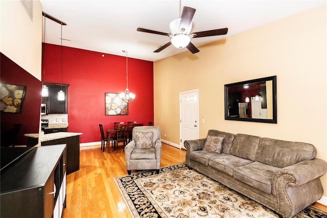 living room with hardwood / wood-style floors, ceiling fan with notable chandelier, and high vaulted ceiling