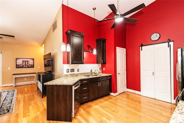 kitchen featuring sink, ceiling fan, light hardwood / wood-style floors, stainless steel appliances, and a barn door