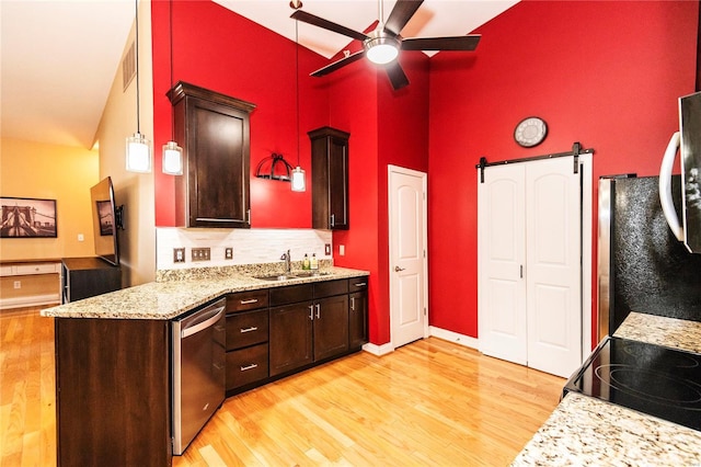 kitchen featuring appliances with stainless steel finishes, pendant lighting, sink, light hardwood / wood-style floors, and a barn door