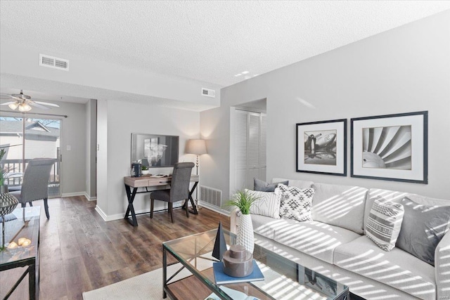 living room with ceiling fan, dark hardwood / wood-style floors, and a textured ceiling