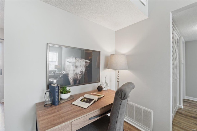 home office with hardwood / wood-style floors and a textured ceiling