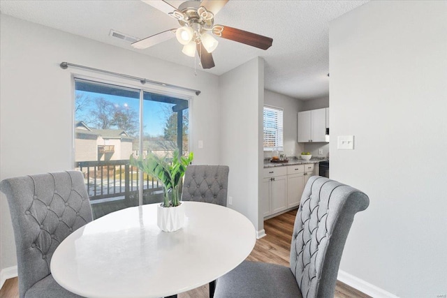 dining space with ceiling fan, hardwood / wood-style floors, and a textured ceiling