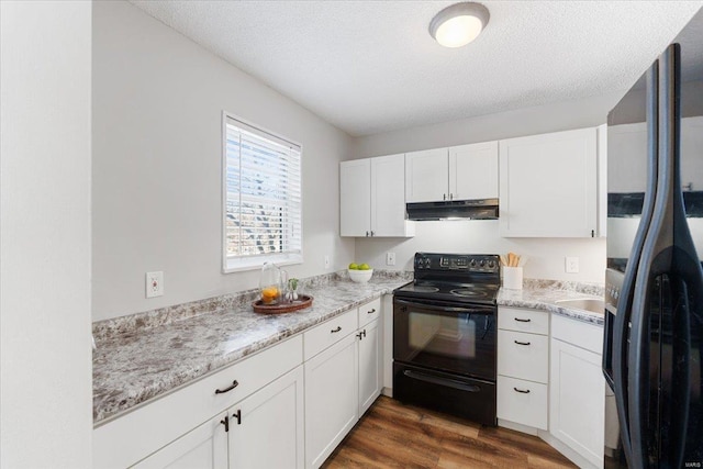 kitchen featuring dark wood-type flooring, white cabinets, a textured ceiling, and black appliances